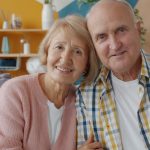 Elderly couple smiling together on a couch.