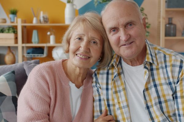 Elderly couple smiling together on a couch.